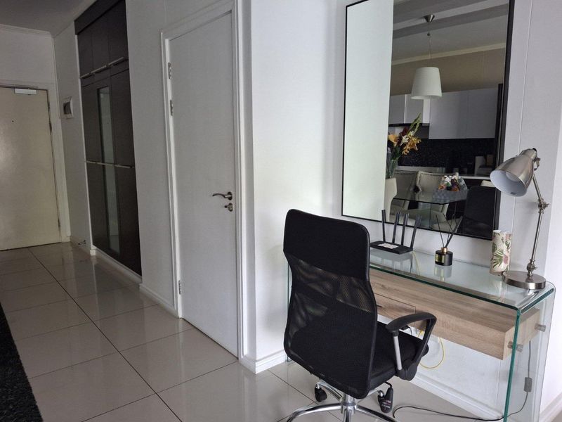 A well-maintained hallway featuring tiled flooring, built-in storage cabinetry, and a large wall-mounted mirror, providing a clean and functional transition space.
