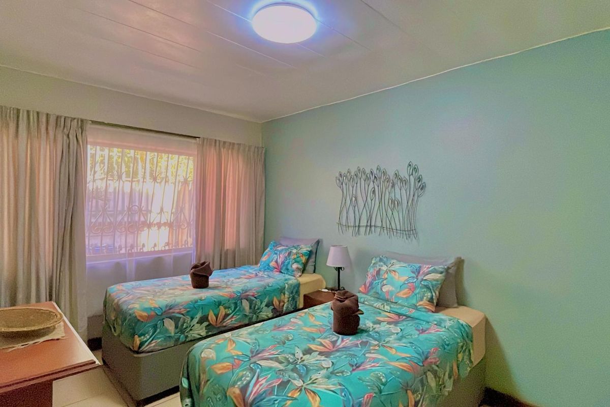 A bedroom featuring a large window with curtains, a ceiling-mounted light fixture, and neutral wall finishes.