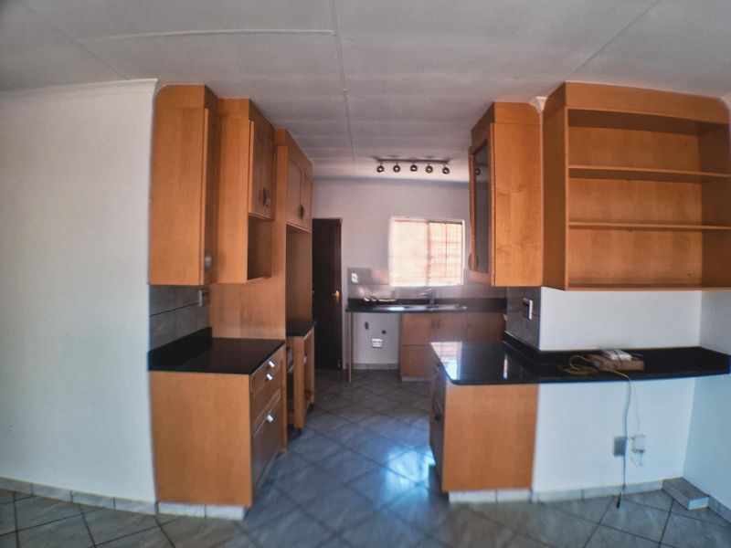A functional kitchen featuring wooden cabinetry, granite countertops, and tiled flooring, offering a clean and practical layout for culinary activities.