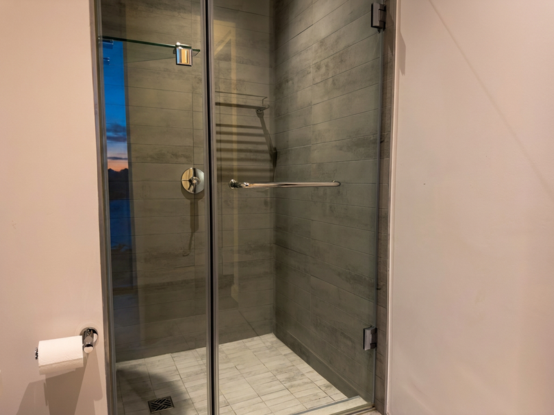 A modern bathroom featuring a glass-enclosed shower with contemporary grey tiling and chrome fixtures.