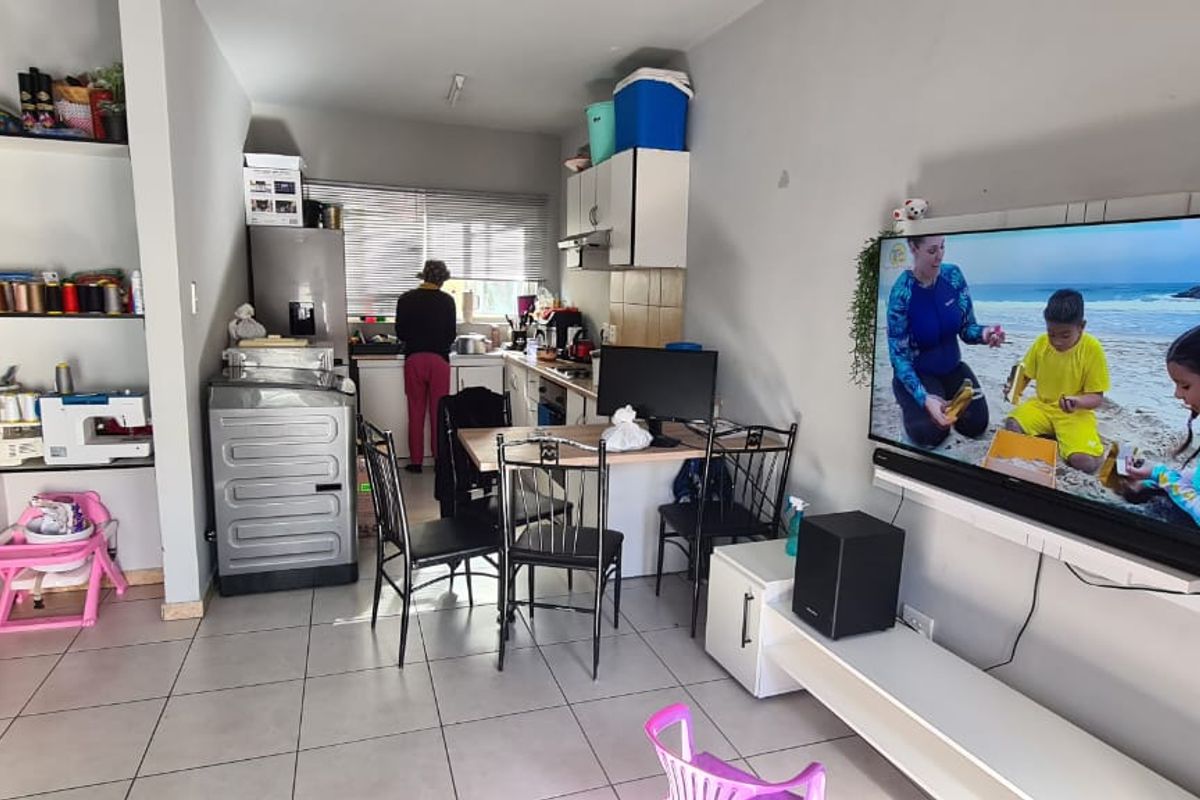 Open-plan living and kitchen area featuring tiled flooring, built-in shelving, and a wall-mounted television unit.