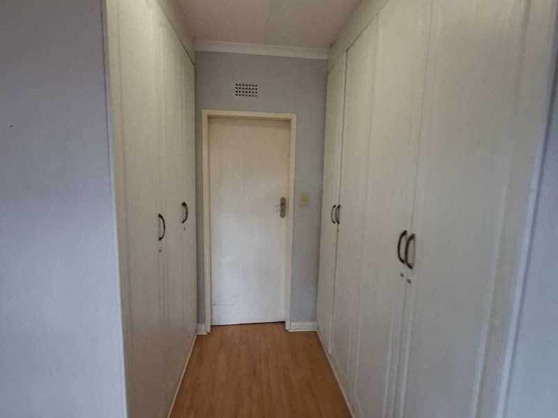 A functional hallway featuring extensive built-in storage cupboards and laminate flooring, providing ample storage space.