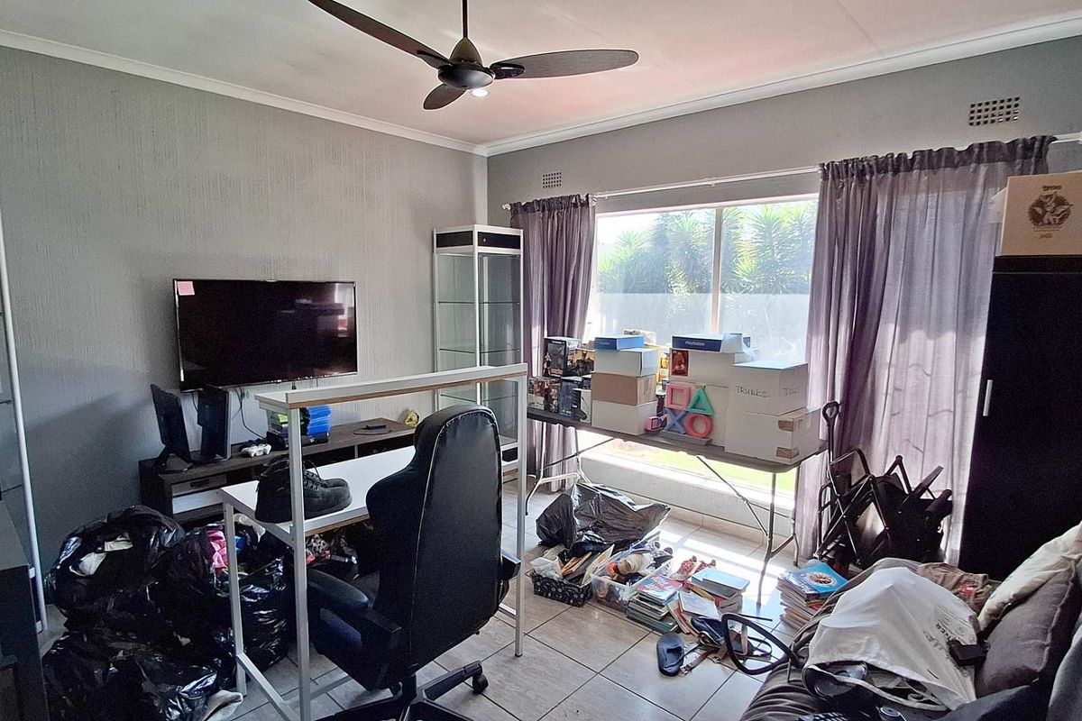 A living room featuring tiled flooring, a ceiling fan, and a large window providing natural light.