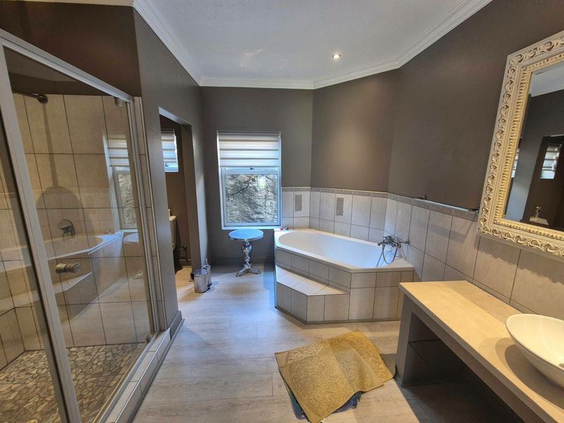 A well-appointed bathroom featuring a built-in corner bathtub, a separate glass-enclosed shower, and a modern vanity with a vessel sink.
