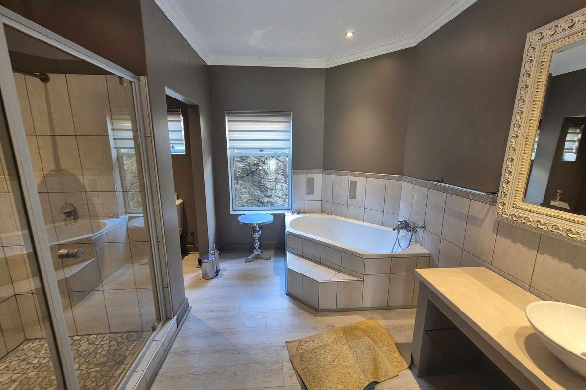 A well-appointed bathroom featuring a built-in corner bathtub, a separate glass-enclosed shower, and a modern vanity with a vessel sink.