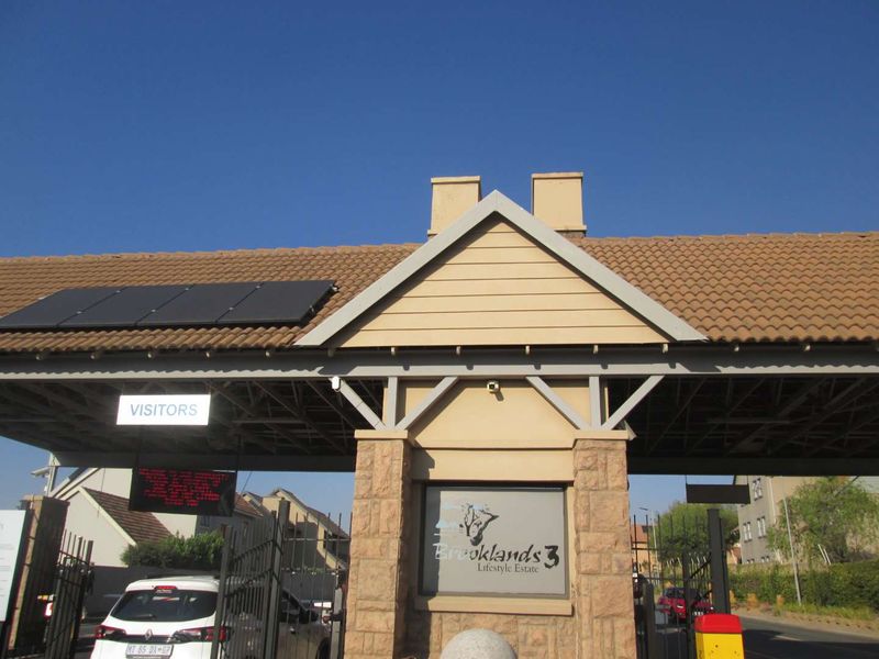 Main entrance gatehouse of Brooklands 3 Lifestyle Estate, featuring stone cladding, tiled roofing, and integrated solar panels for security access control.