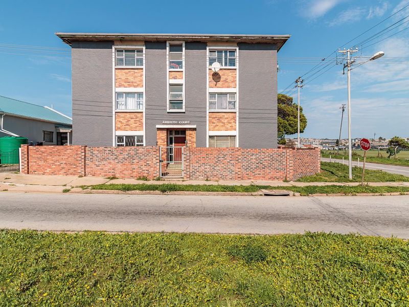 Front elevation of Ambrose Court, a multi-story apartment building featuring a brick and painted concrete facade with a perimeter brick wall.