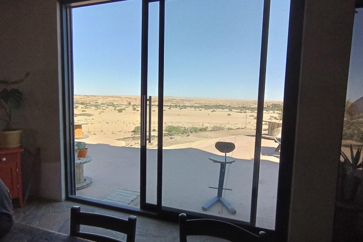 Interior view looking out through large sliding glass doors onto a spacious patio and expansive arid landscape.