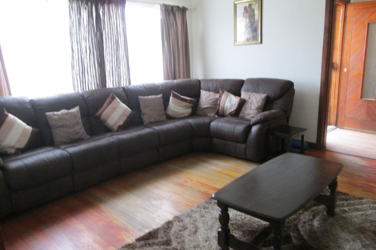 A living room featuring timber flooring and a doorway leading to an adjacent space.