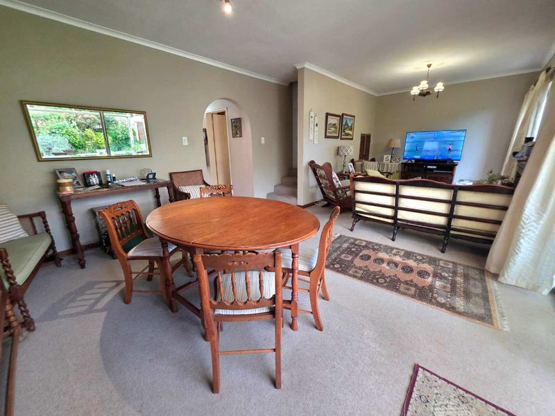 Spacious open-plan living and dining area featuring an arched entryway and staircase, providing a functional layout for family living.