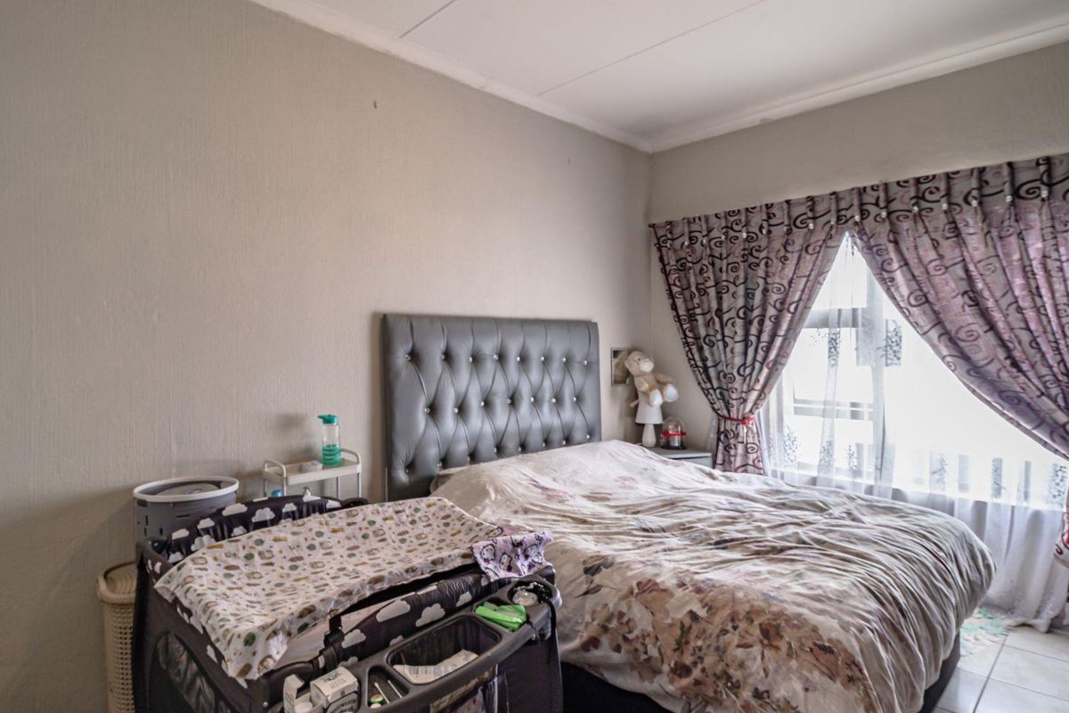A bedroom featuring tiled flooring and a window with curtains, providing a functional space for rest.
