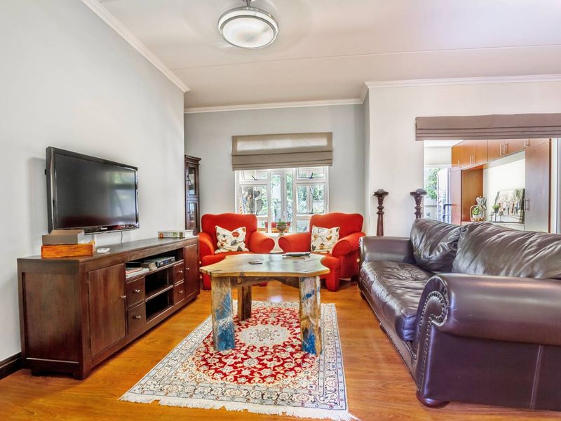 A comfortable living room featuring laminate flooring, neutral walls, and a window with a roller blind, providing a functional and inviting space.