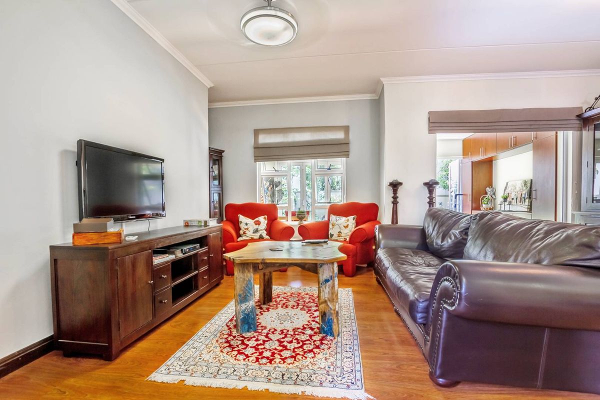 A comfortable living room featuring laminate flooring, neutral walls, and a window with a roller blind, providing a functional and inviting space.