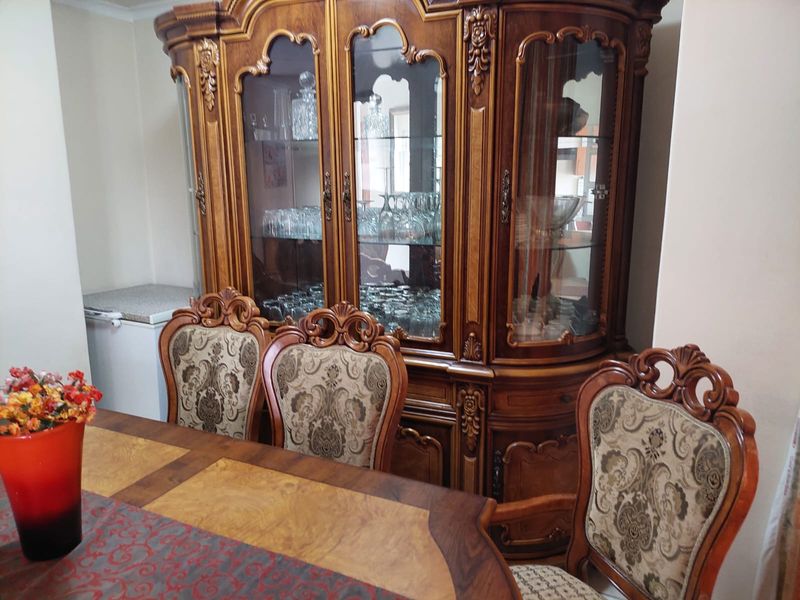 A dining room area featuring a large wooden display cabinet and dining furniture.