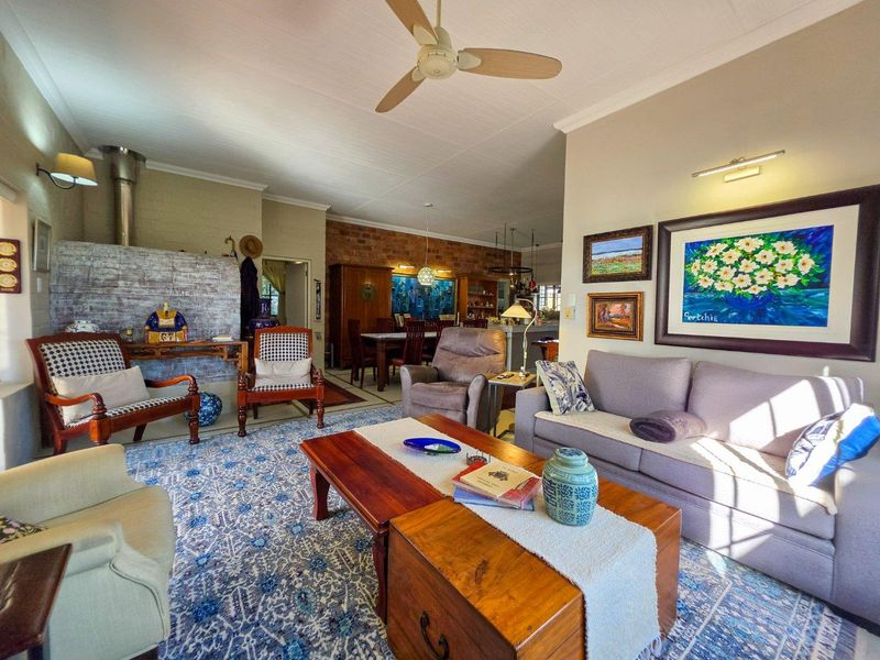 Spacious open-plan living and dining area featuring a cozy fireplace, exposed brick accents, and a ceiling fan, creating a warm and inviting atmosphere.