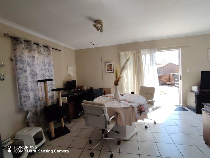 A living area featuring tiled flooring and a sliding glass door providing access to an outdoor patio space.
