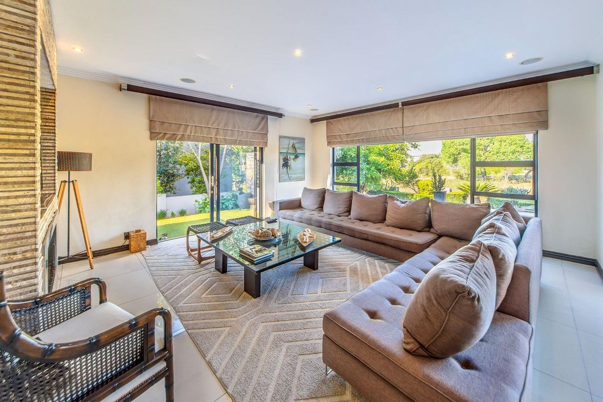 Spacious living room featuring a stone-clad fireplace, large sliding glass doors, and expansive windows that provide ample natural light and garden views.