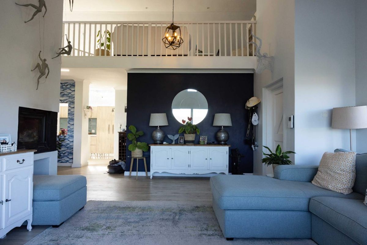 Spacious living room featuring a fireplace, laminate flooring, and an open mezzanine level with a white timber balustrade.
