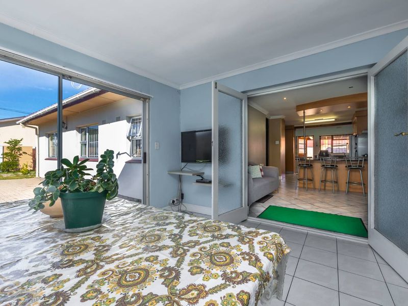 Open plan living area featuring tiled floors, sliding doors to the exterior, and a direct view into the adjacent kitchen with breakfast bar seating.
