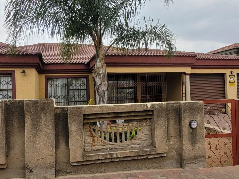 Front elevation of a single-story house featuring a tiled roof, secure boundary wall with decorative elements, and an integrated garage.