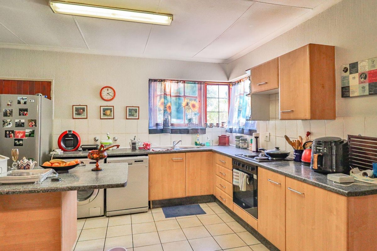 A functional kitchen featuring light wood cabinetry, granite-look countertops, tiled flooring, and integrated oven and hob, offering a practical layout for daily meal preparation.