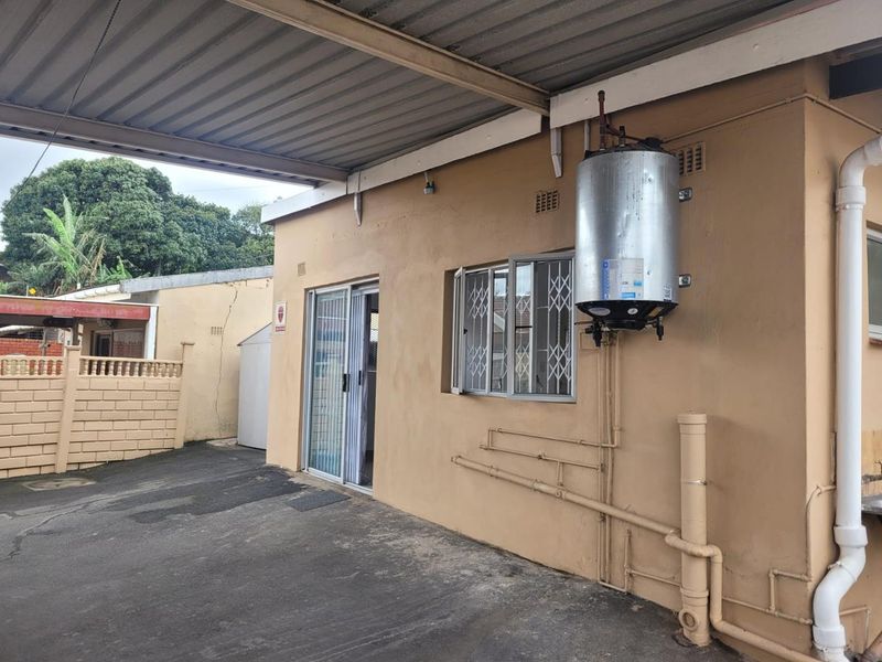 Rear exterior view of the property featuring a covered patio area, sliding door access, and an externally mounted electric water heater.