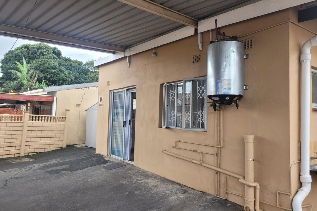 Rear exterior view of the property featuring a covered patio area, sliding door access, and an externally mounted electric water heater.