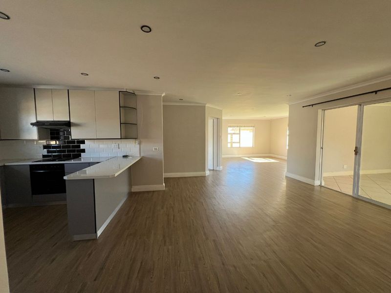 Spacious open-plan living area featuring a modern kitchen with built-in appliances, stone countertops, and seamless flow to the adjacent living space.