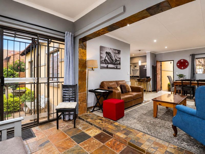 Open-plan living and dining area featuring slate tile flooring, a stone-clad feature archway, and direct access to the outdoor patio through sliding security doors.