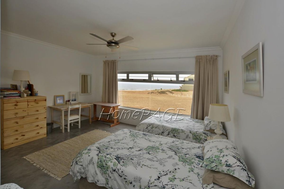 Spacious bedroom featuring a large window with scenic coastal views, ceiling fan, and neutral finishes.