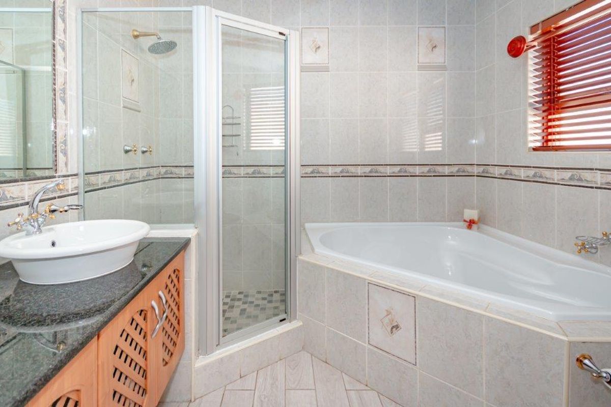 A functional bathroom featuring a corner bathtub, a separate glass-enclosed shower, and a vanity with a granite countertop.