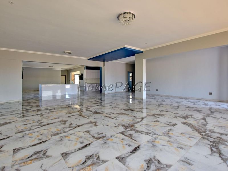 Spacious open-plan living and kitchen area featuring polished marble-look floor tiles and a modern recessed ceiling design.