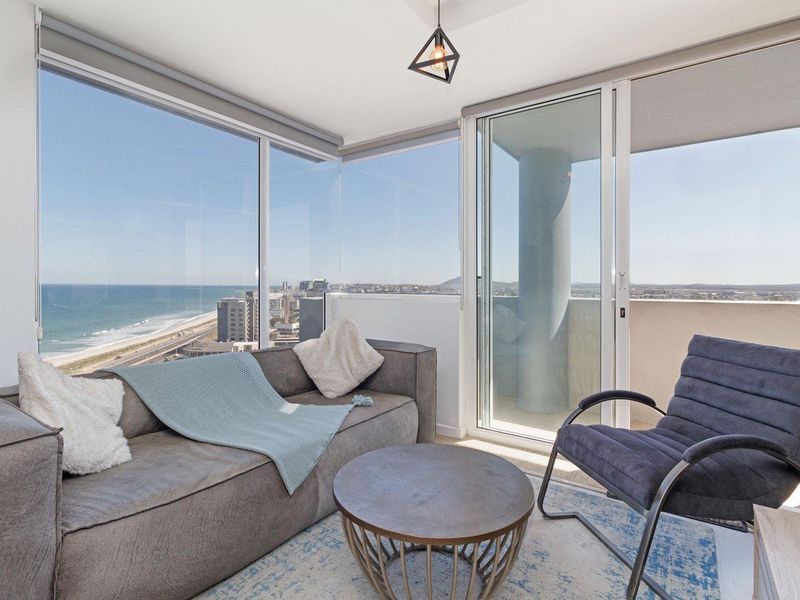Bright living area featuring floor-to-ceiling windows with panoramic ocean views and direct access to a private balcony.