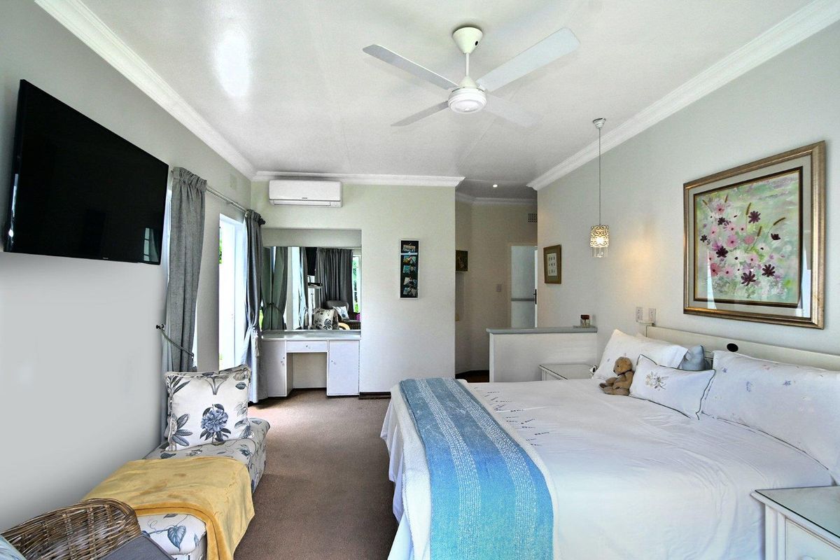 A well-maintained bedroom featuring a ceiling fan, split-system air conditioning, and a built-in vanity area with crown molding details.