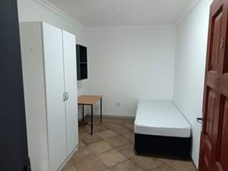 A functional bedroom featuring tiled flooring and coved ceiling details, providing a simple and clean living space.