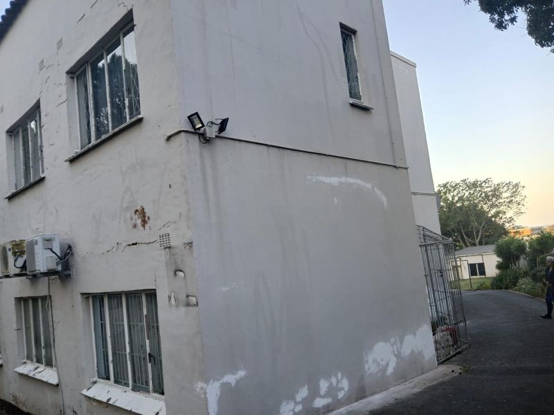 Exterior view of the apartment building showing signs of wear, including cracked plaster, peeling paint, and visible rust stains on the facade.