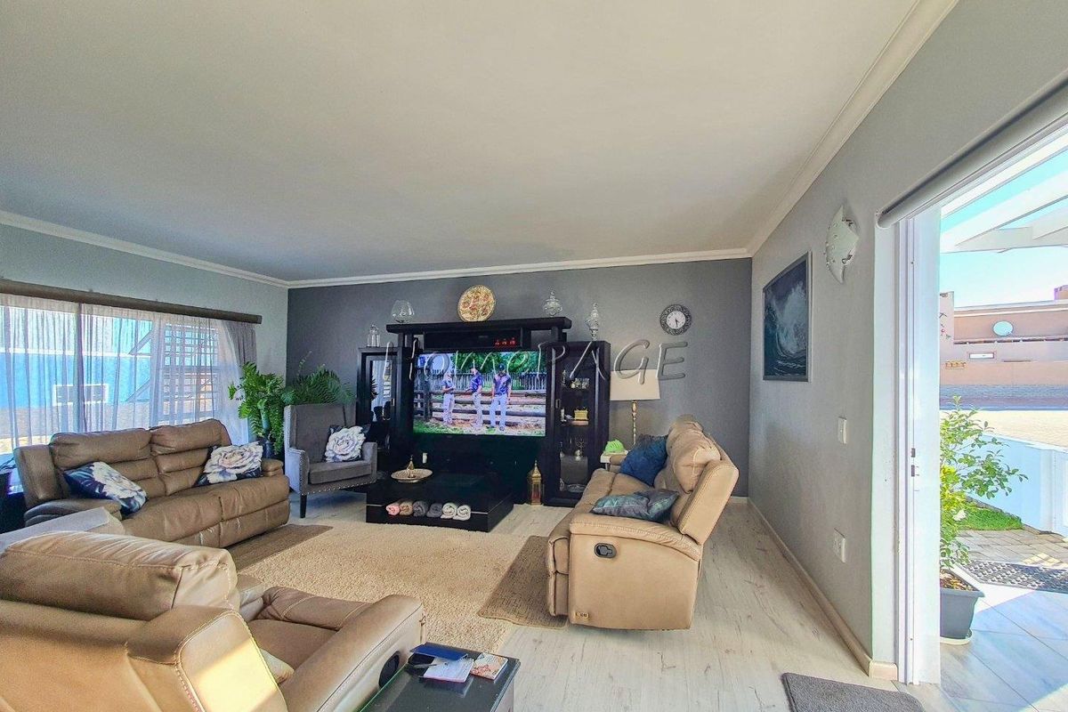 Spacious living room featuring light-toned laminate flooring, a feature wall, and direct access to an outdoor patio area.