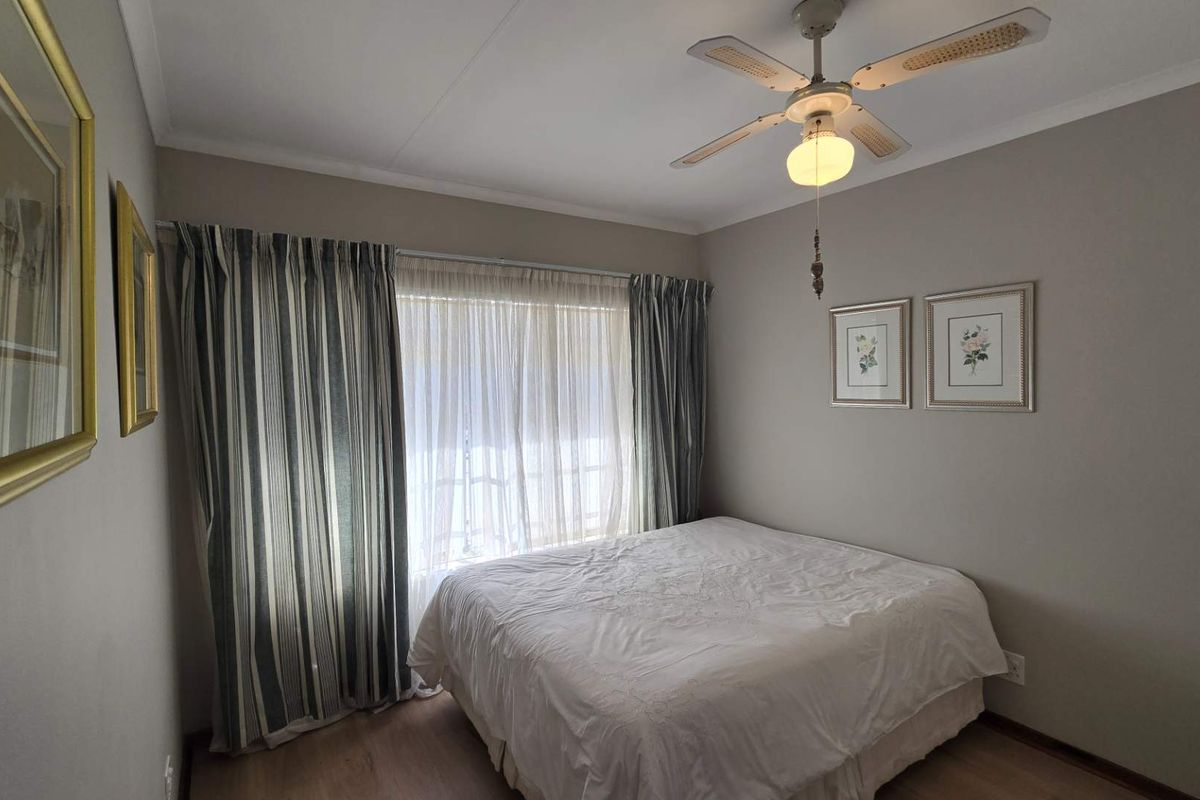 A well-maintained bedroom featuring laminate flooring, a central ceiling fan, and neutral wall tones, providing a comfortable and functional living space.