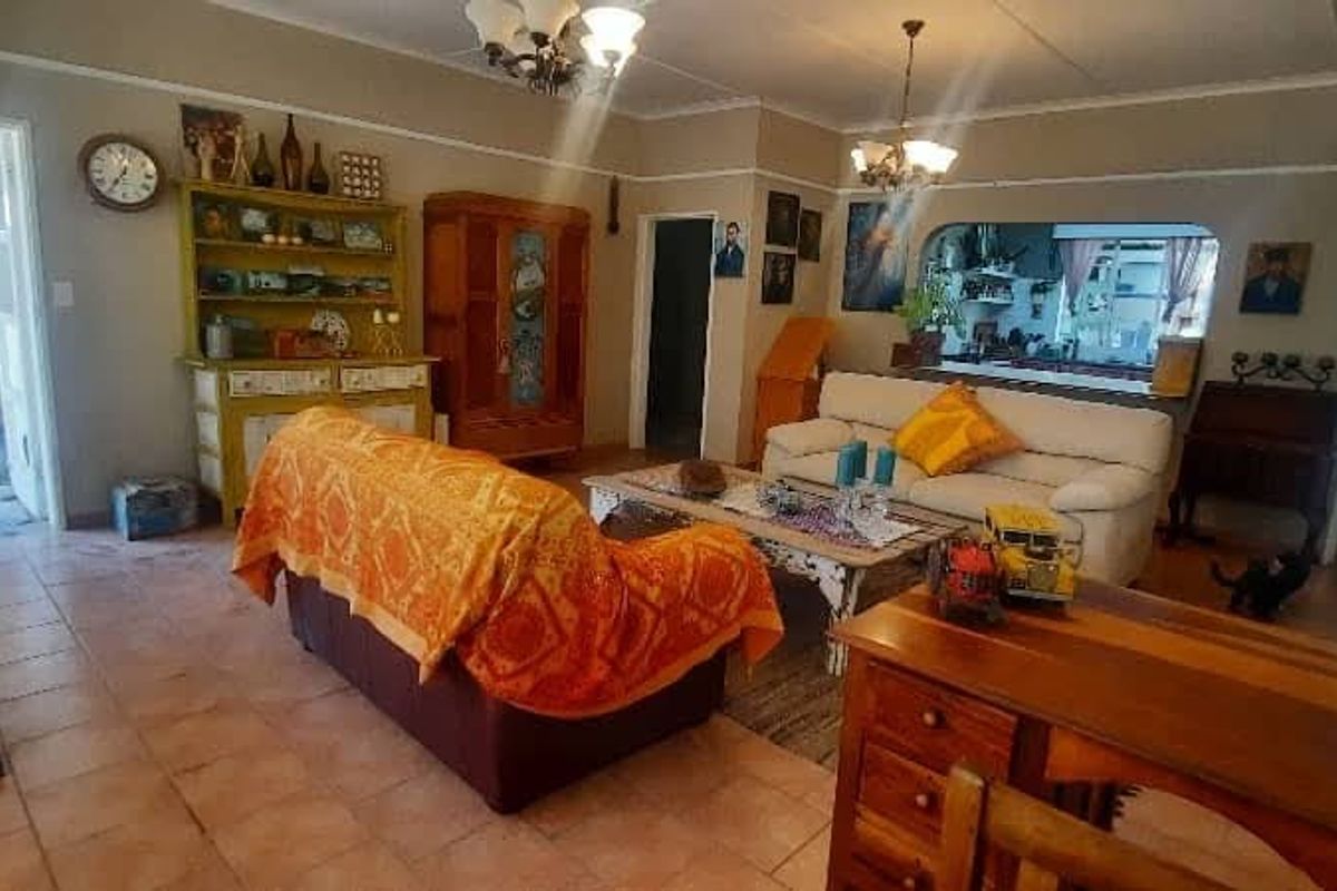 A spacious living room featuring tiled flooring, a pass-through window to the kitchen, and direct access to an outdoor patio area.