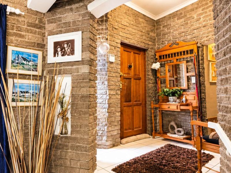 Welcoming entrance hall featuring rustic exposed brick walls, tiled flooring, and a solid wooden front door.