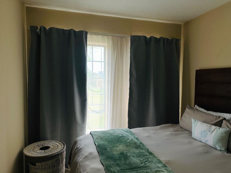 A bedroom featuring a window with installed curtain rods and curtains, providing natural light to the space.