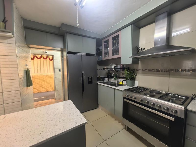 Modern kitchen featuring stone countertops, built-in cabinetry, stainless steel gas stove with extractor fan, and tiled finishes, leading to an adjacent outdoor area.