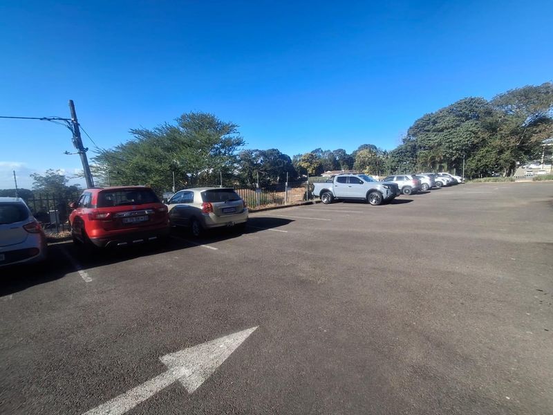 An open-air asphalt parking area featuring marked bays and perimeter fencing, providing convenient vehicle access for the business premises.