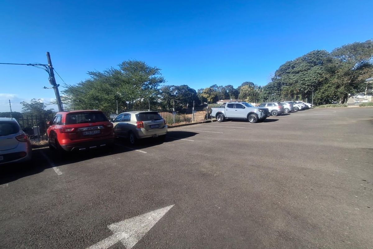 An open-air asphalt parking area featuring marked bays and perimeter fencing, providing convenient vehicle access for the business premises.