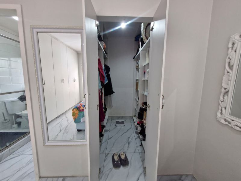 A bedroom featuring built-in cupboards, marble-look tiled flooring, and direct access to an en-suite bathroom.