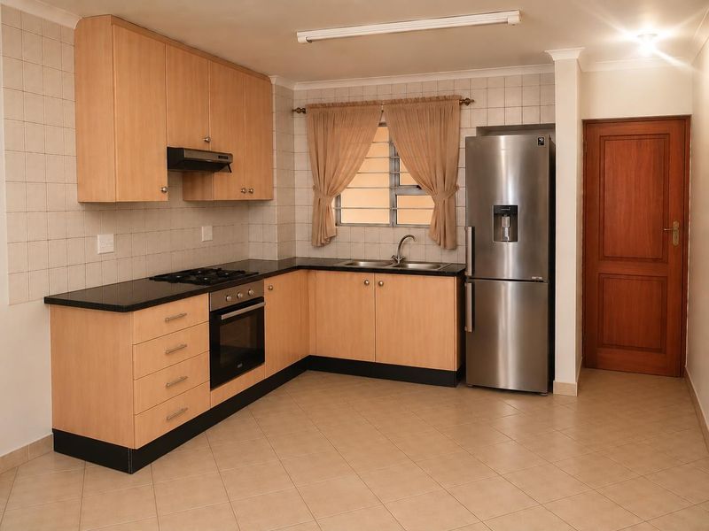 A functional kitchen featuring light wood cabinetry, granite countertops, built-in oven, gas hob, and tiled flooring, offering a clean and practical workspace.