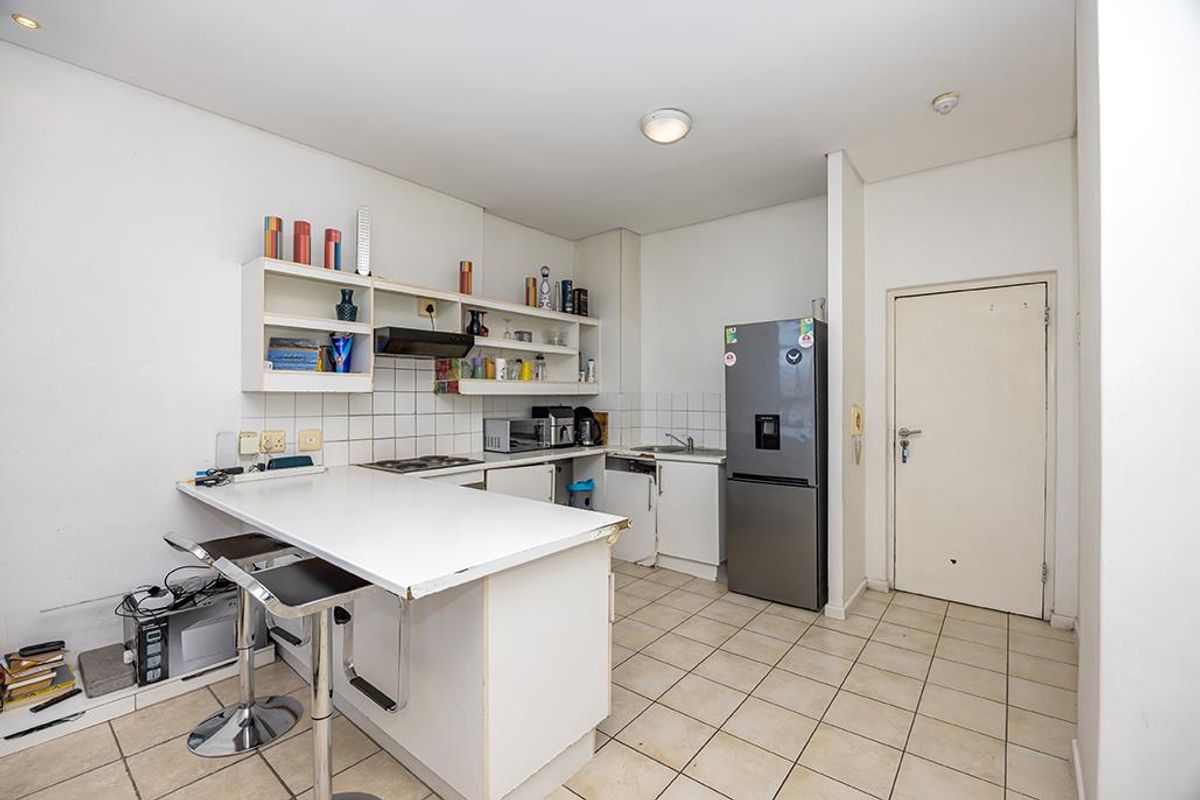 A functional kitchen featuring built-in cabinetry, a tiled backsplash, a breakfast bar, and tiled flooring, offering potential for modernization and aesthetic updates.