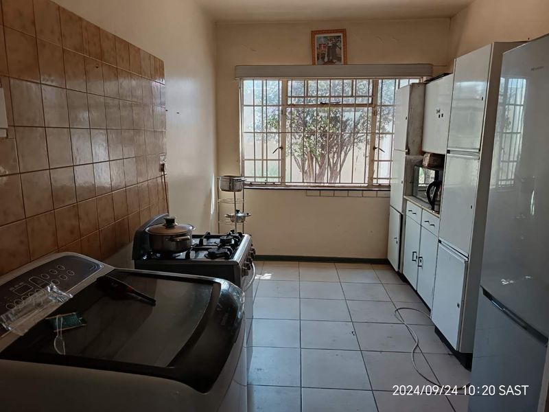 A functional kitchen featuring tiled flooring, a gas stove, and built-in cabinetry with a tiled splashback, offering potential for modernization.