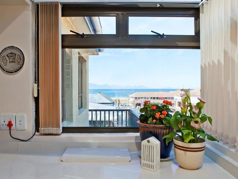 A clear view of the ocean and coastal town through a window with fitted vertical blinds and integrated electrical power points.
