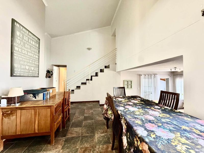 Open plan living and dining area featuring tiled flooring and a staircase with a modern metal balustrade.